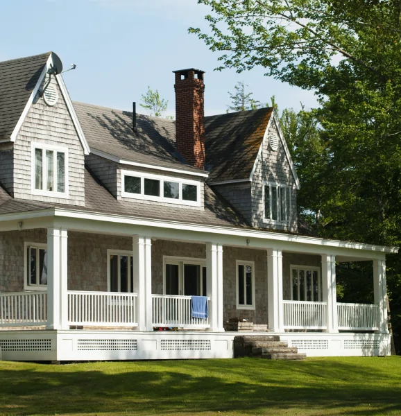 grey house with front porch and brick chimney