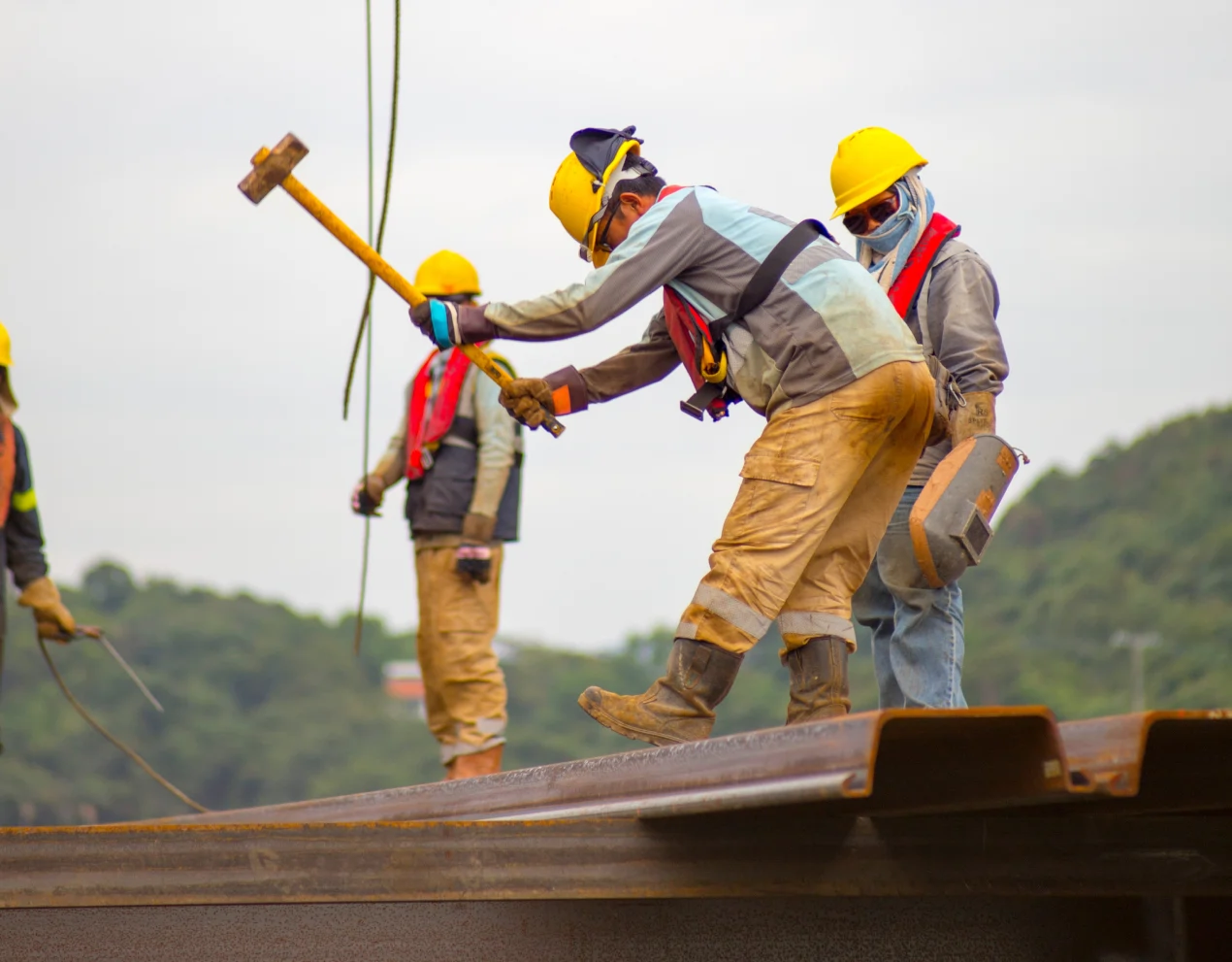 construction workers with yellow hardhats using hammers